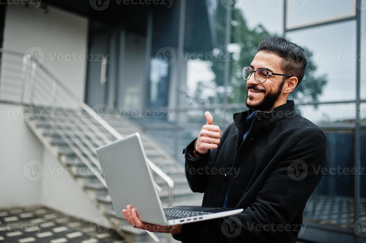 mezzo orientale imprenditore contro ufficio edificio parlare su video chiamata, avere ragnatela conferenza con colleghi di il computer portatile. foto