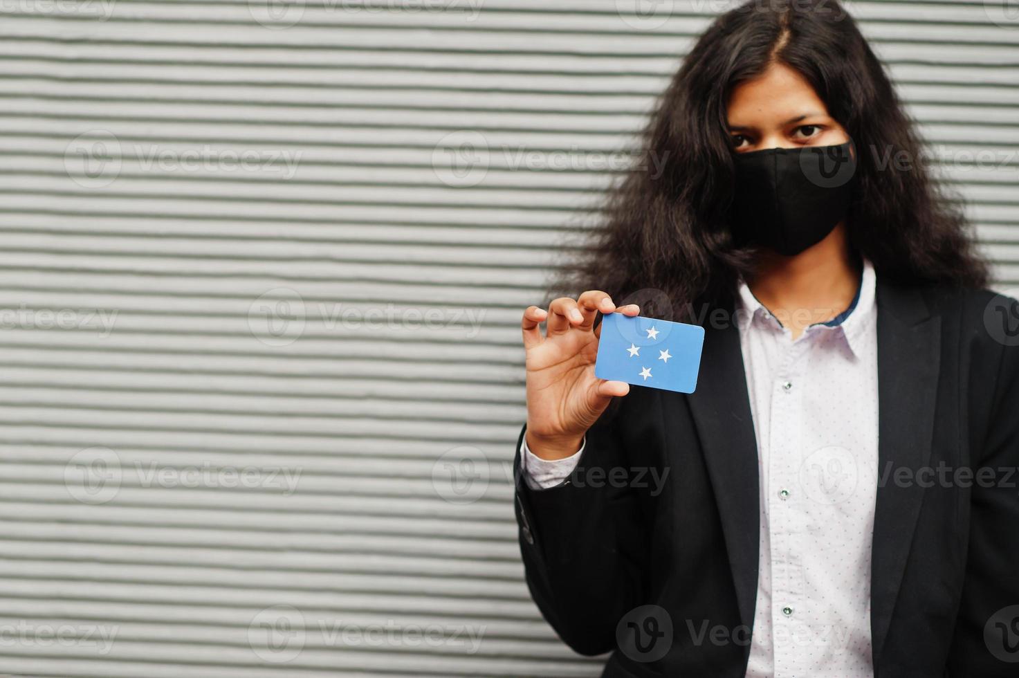 asiatico donna a formale indossare e nero proteggere viso maschera hold micronesia bandiera a mano contro grigio sfondo. coronavirus a nazione concetto. foto