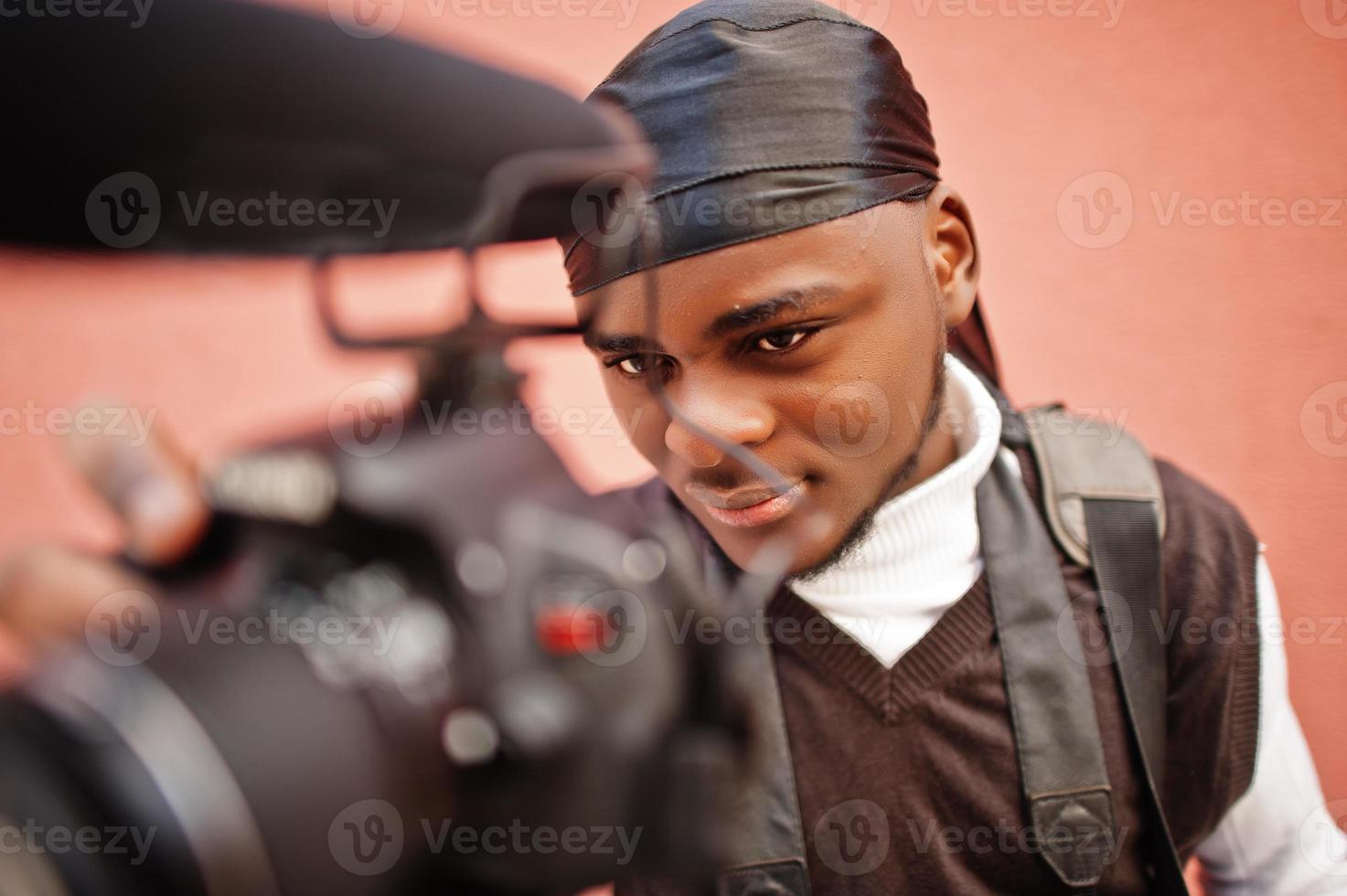 giovane professionale africano americano operatore video Tenere professionale telecamera con professionista attrezzatura. afro cineoperatore indossare nero duraq fabbricazione un' video. foto