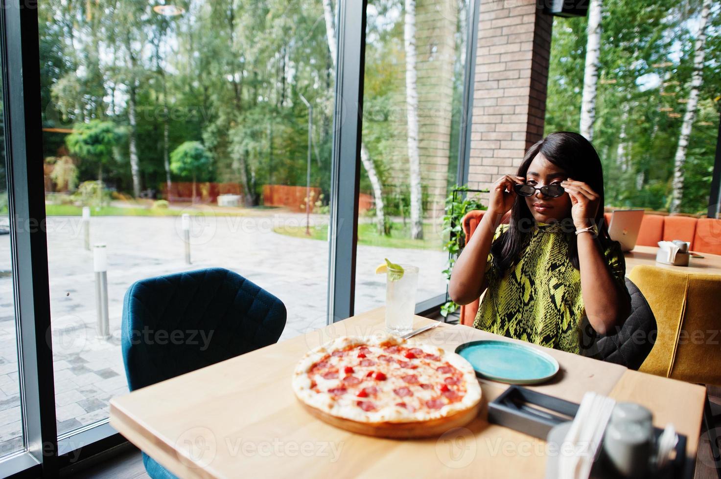 fascino africano americano donna mangiare Pizza a ristorante. foto