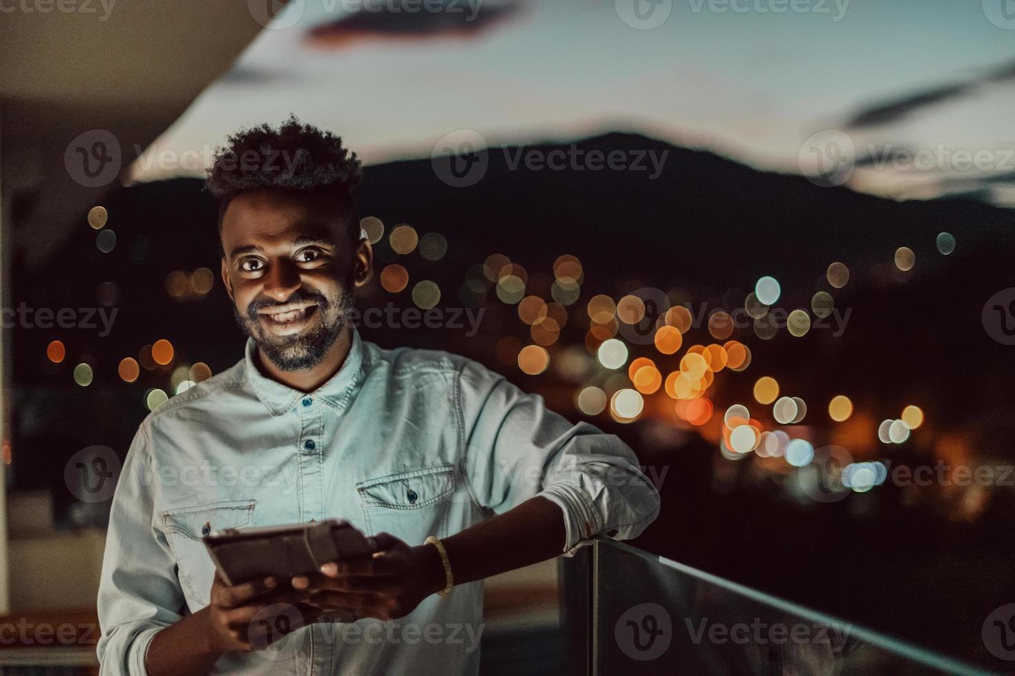 il giovane uomo su un urbano città strada a notte sms su smartphone con bokeh e neon città luci nel il sfondo. foto