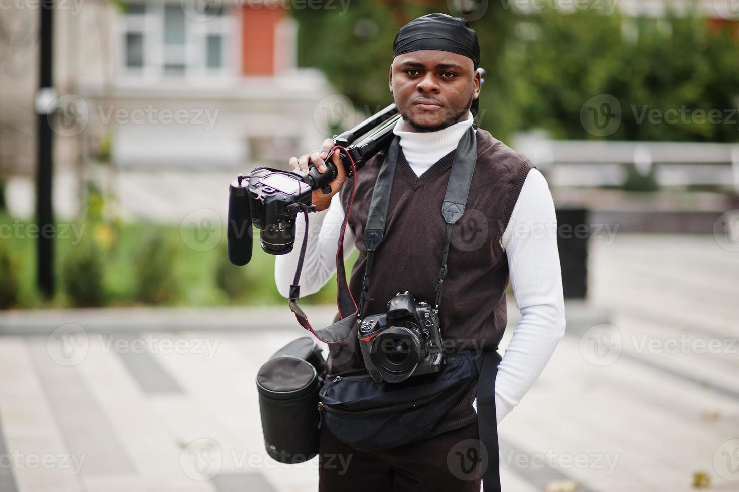 giovane professionale africano americano operatore video Tenere professionale telecamera con professionista attrezzatura. afro cineoperatore indossare nero duraq fabbricazione un' video. foto