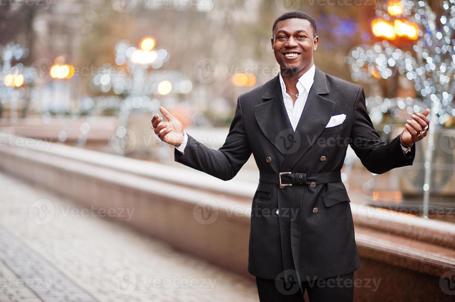 ritratto di giovane e bello africano americano uomo d'affari nel completo da uomo a piedi su cemter di città con ghirlande. foto