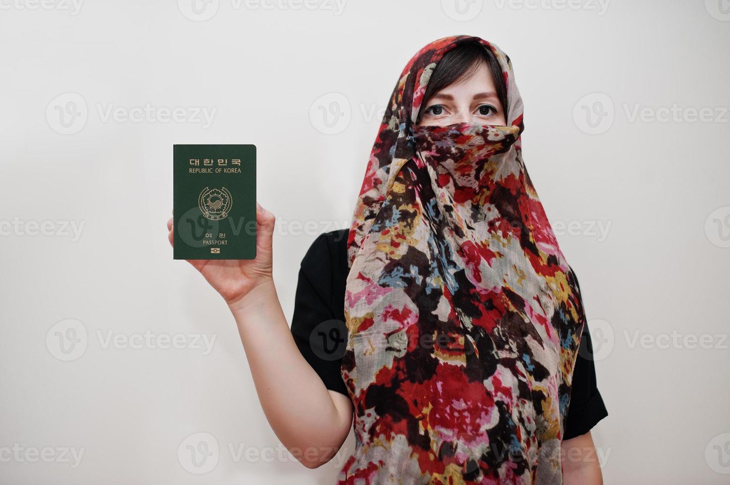 giovane arabo musulmano donna nel hijab Abiti hold repubblica di Corea passaporto su bianca parete sfondo, studio ritratto. foto