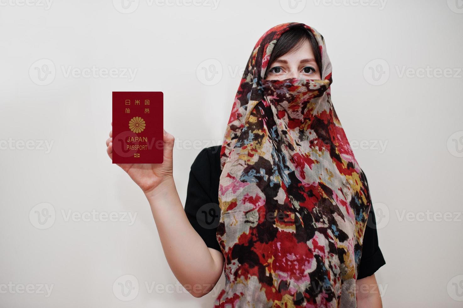giovane arabo musulmano donna nel hijab Abiti hold Giappone passaporto su bianca parete sfondo, studio ritratto. foto