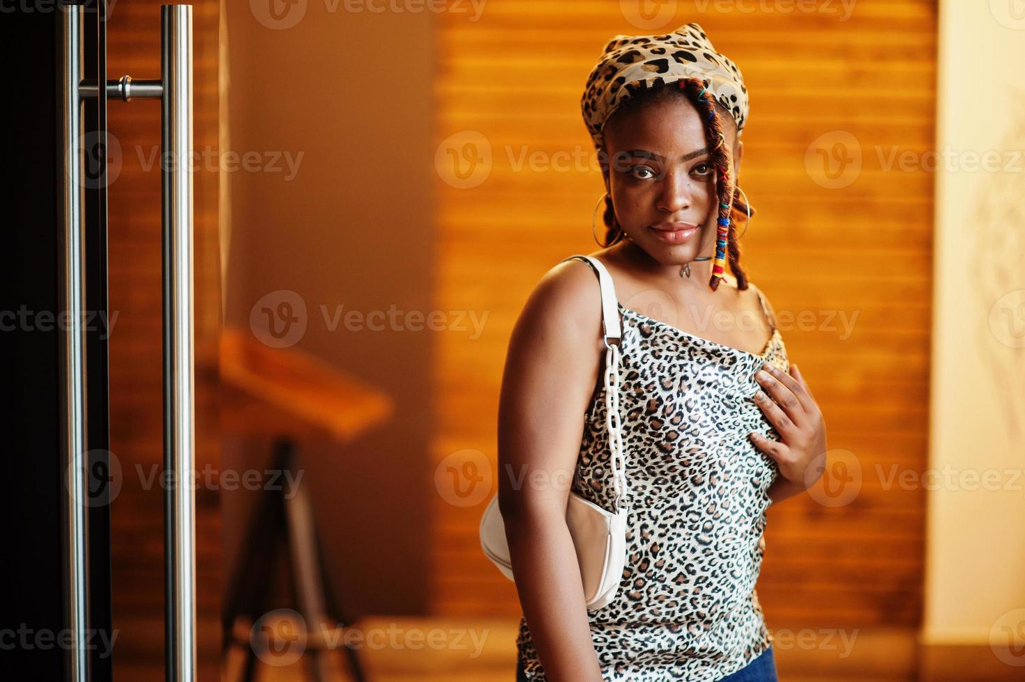 bello africano americano donna con dreadlocks nel leopardo attrezzatura a bar. bellissimo freddo alla moda nero giovane ragazza interno. foto