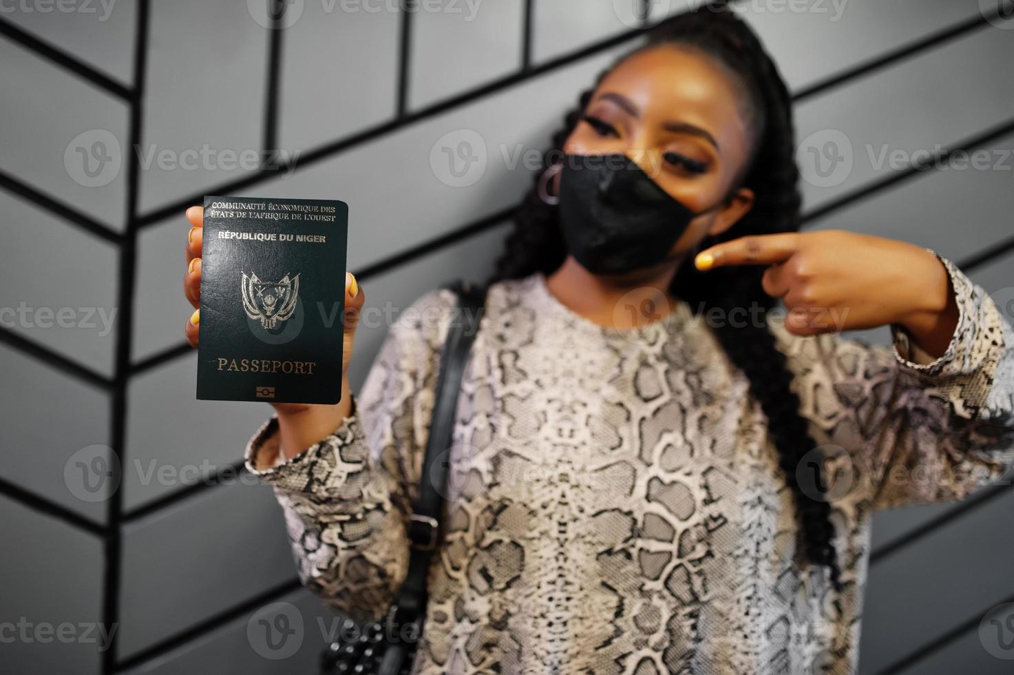 africano donna indossare nero viso maschera mostrare Niger passaporto nel mano. coronavirus nel Africa nazione, confine chiusura e quarantena, virus scoppio concetto. foto