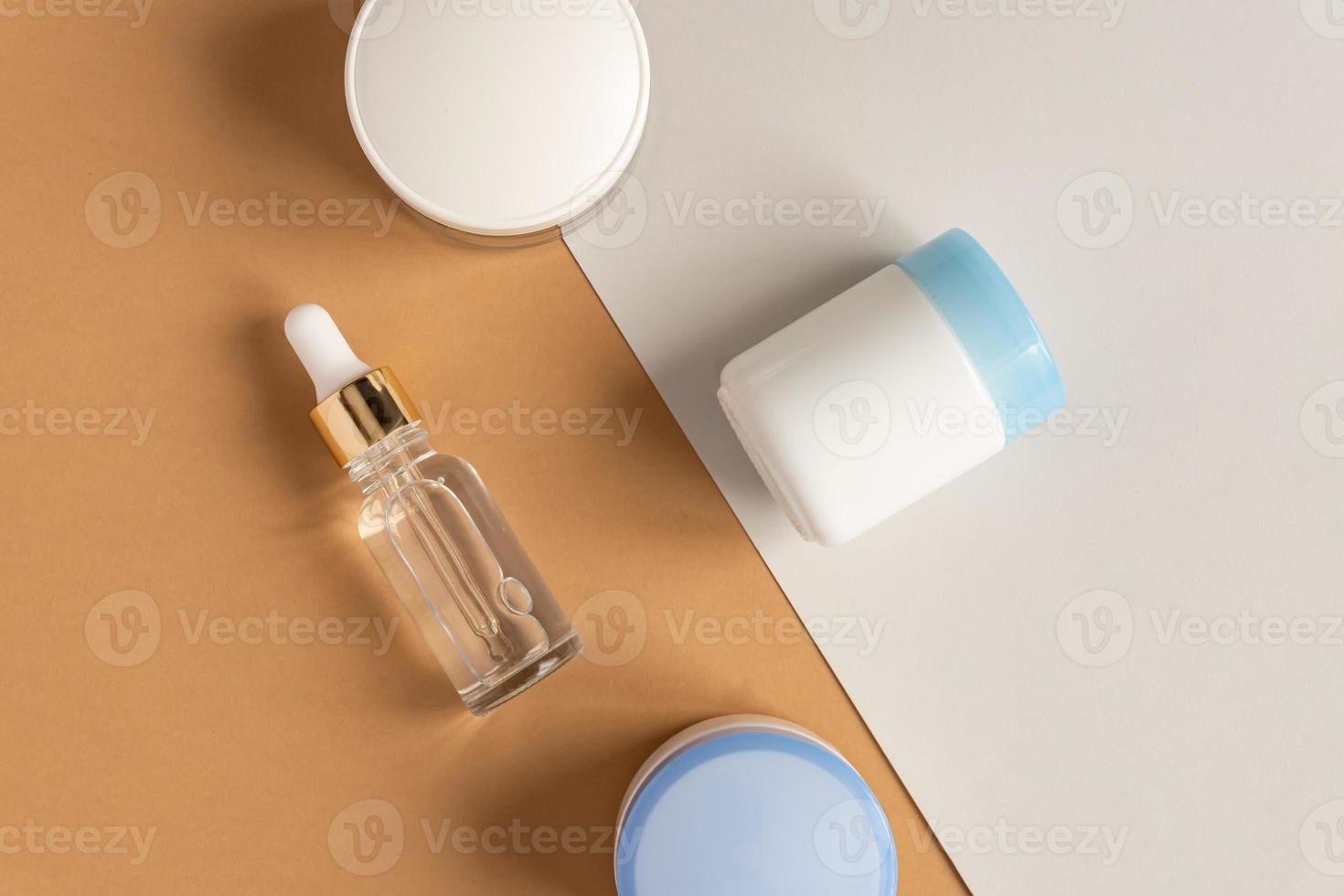 anti età collagene facciale siero nel trasparente bicchiere bottiglia con oro pipetta e viso crema su Doppio beige e grigio sfondo. naturale biologico cosmetico bellezza concetto. foto