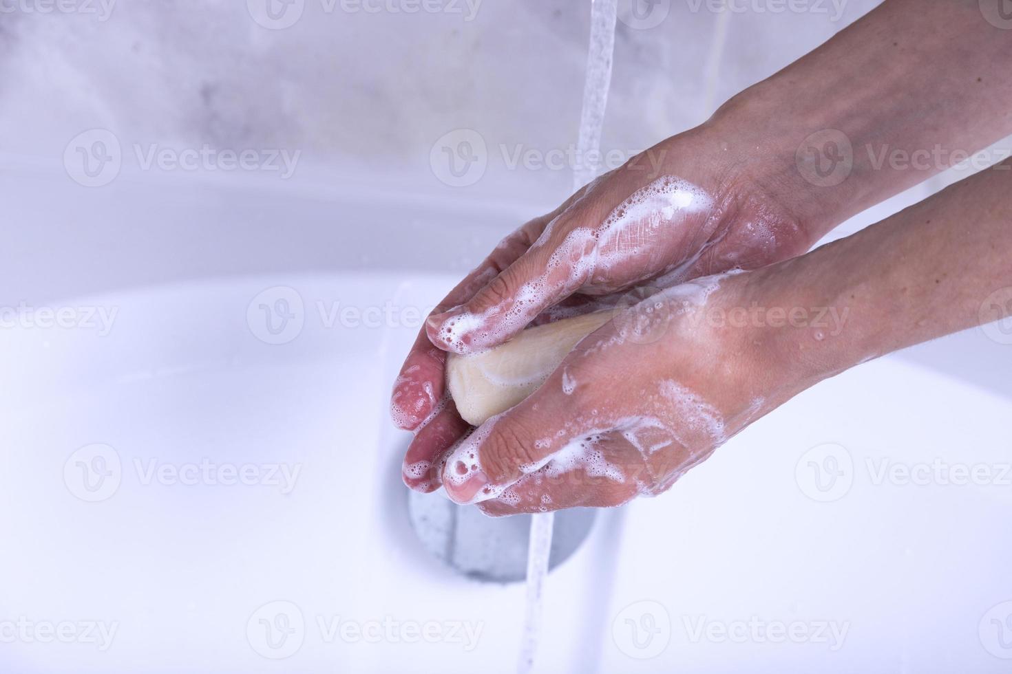 mano lavaggio processi. femmina mani sotto il rubinetto con acqua nel il bagno. foto