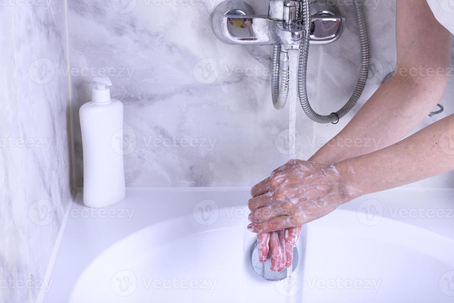 mano lavaggio processi. femmina mani sotto il rubinetto con acqua nel il bagno. foto