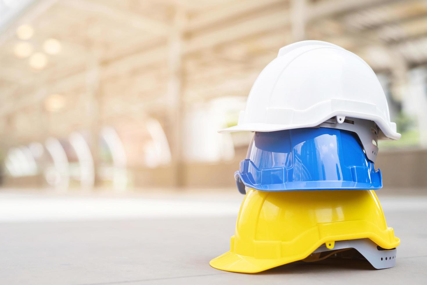 bianca, giallo e blu difficile sicurezza casco cappello per sicurezza progetto di operaio come ingegnere o lavoratore, su calcestruzzo pavimento foto