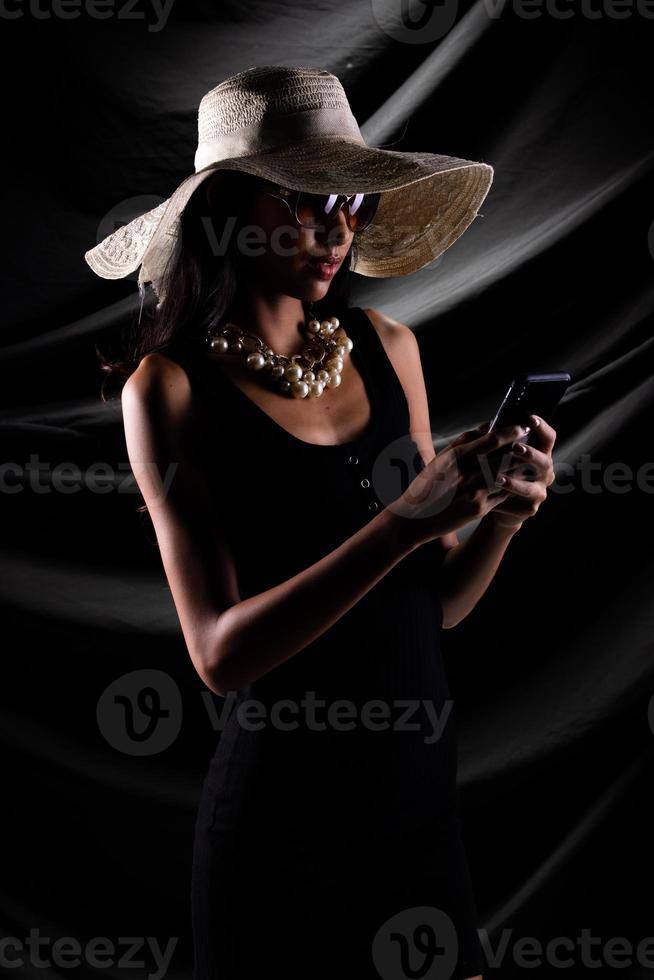 silhouette di giovane donna hold oro bitcoin criptovaluta commercio in linea al di sopra di drappo tenda nero sfondo, bellissimo femmina pose metà corpo come lusso perla trascurare cappello sole bicchieri foto