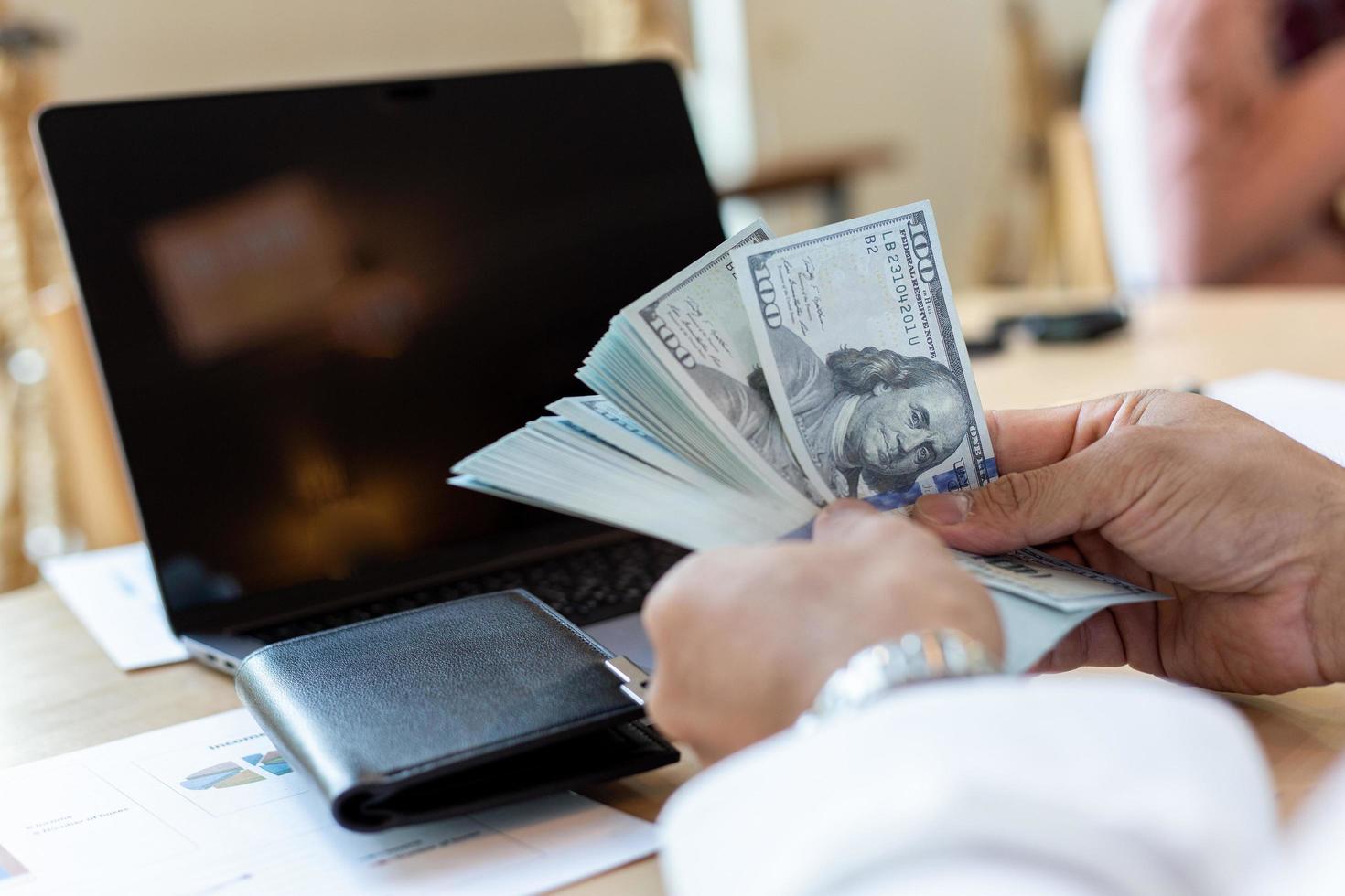 uomo d'affari gestisce denaro al lavoro per analizzare i rendiconti finanziari foto