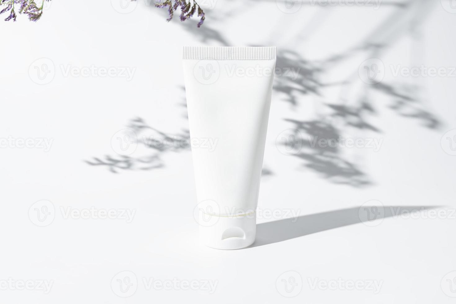 bianca cosmetico tubo per viso o corpo crema, detersivo o shampoo su un' bianca sfondo con le foglie ombre. concetto di minimalismo nel cosmetico confezione. copia spazio. foto