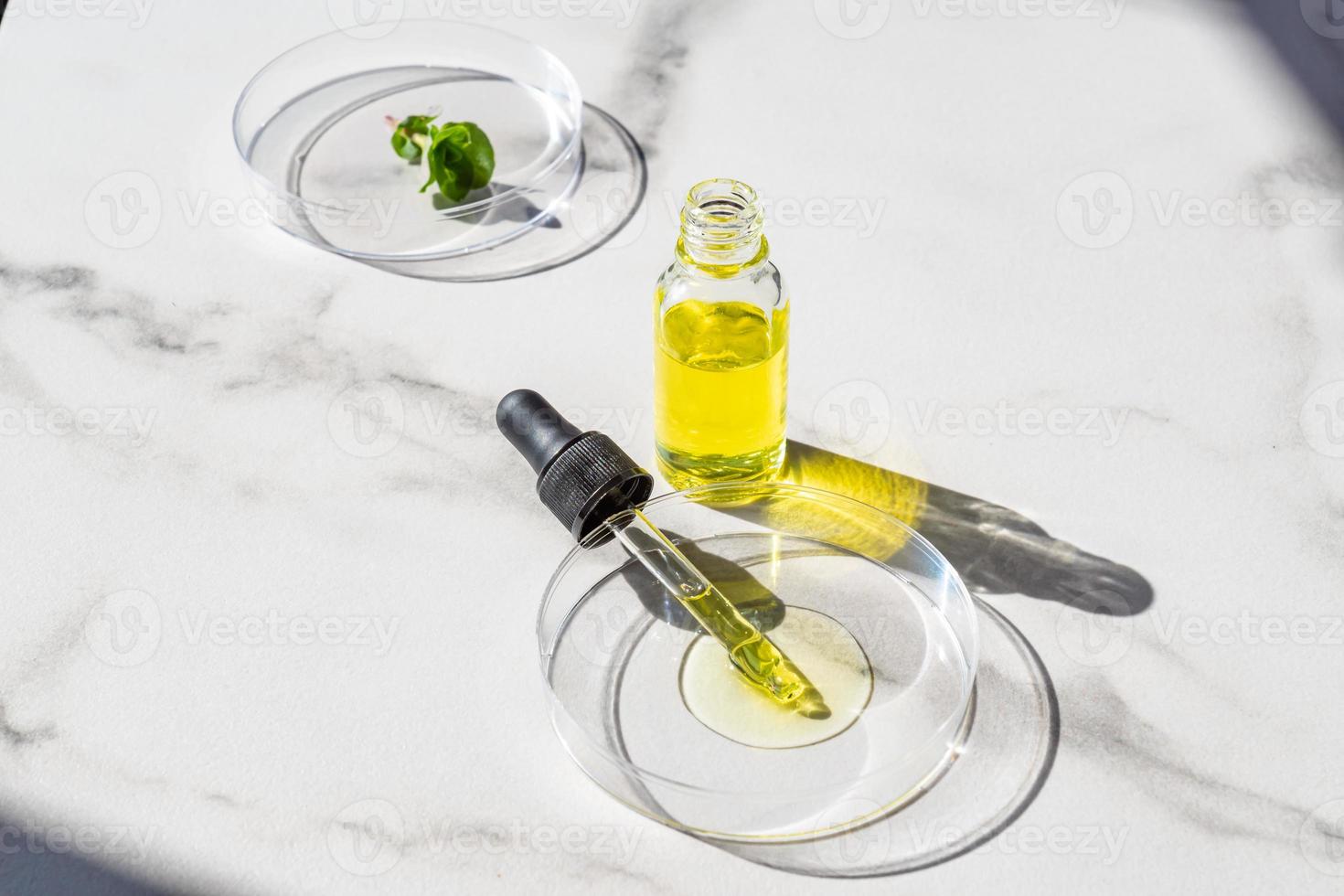 cosmetico pipetta siero su un' petri piatto con menta le foglie su bianca marmo sfondo. cosmetologia e prodotti farmaceutici concetto. acido peeling, viso olio, collagene foto