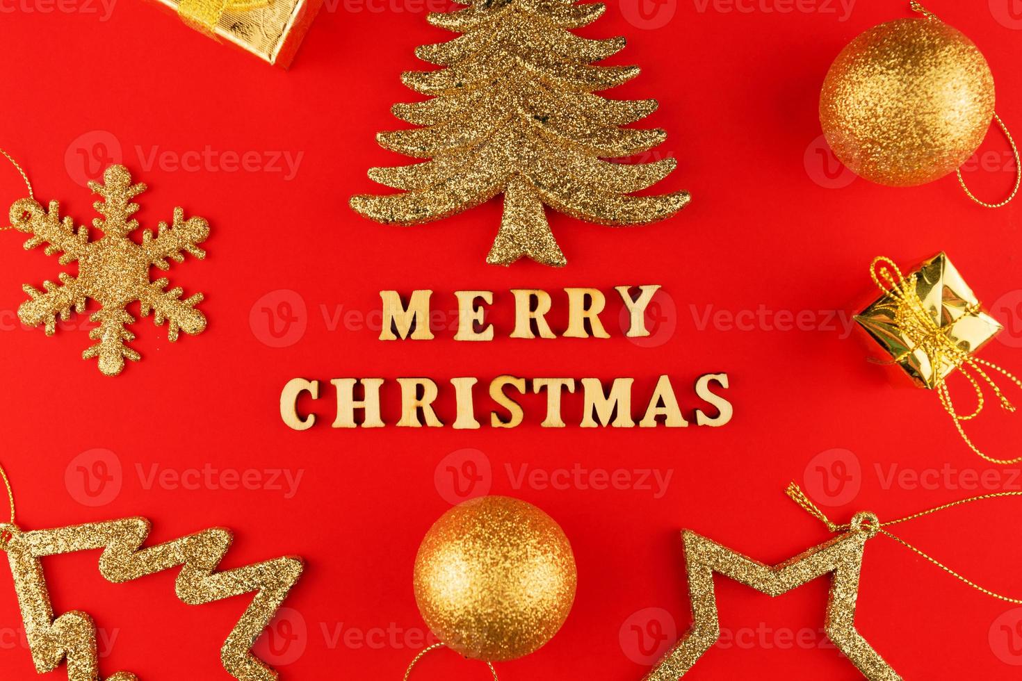 festivo saluto carta. allegro Natale lettering su rosso carta con d'oro luccicante giocattoli. foto