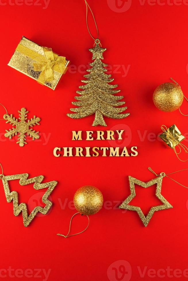 festivo saluto carta. allegro Natale lettering su rosso carta con d'oro luccicante giocattoli. foto