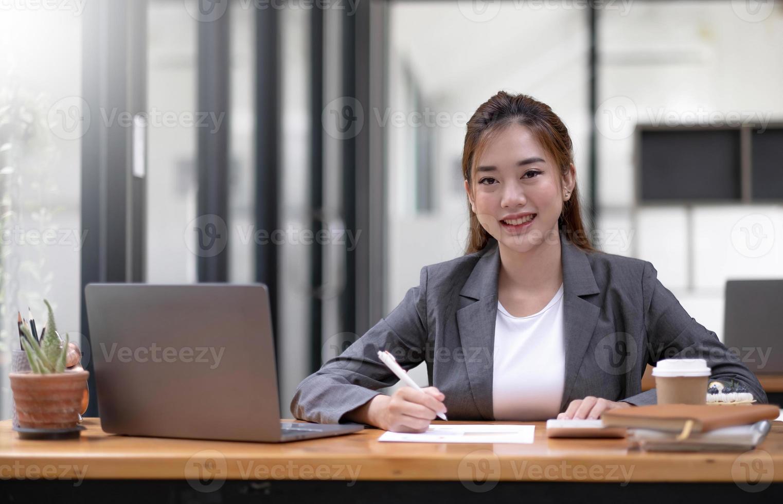 asiatico imprenditrice seduta Lavorando a il ufficio. guardare a telecamera. foto