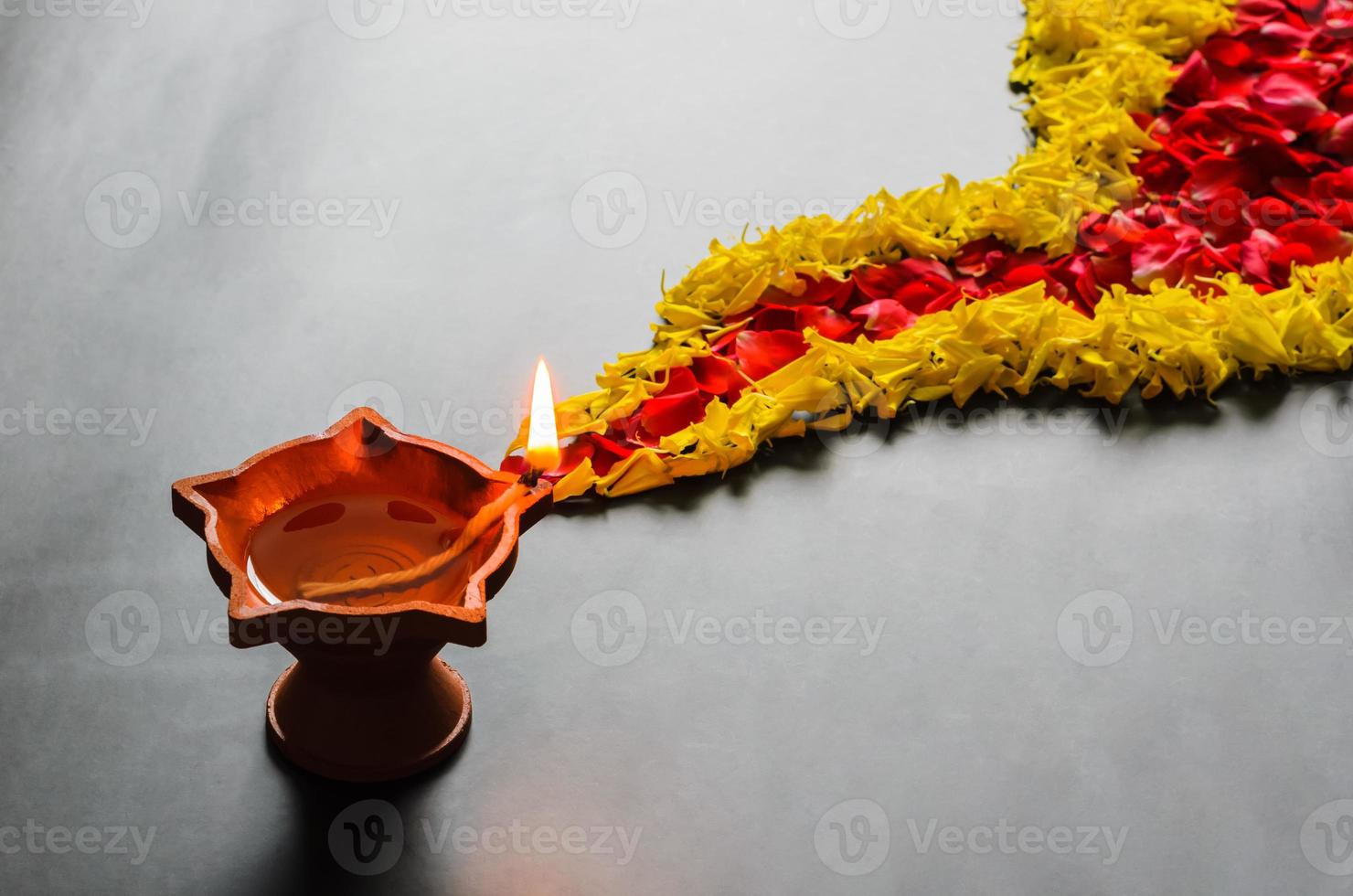 argilla diya lampada con decorativo calendula e rosa fiore petali rangoli su il pavimento per Diwali Festival. foto