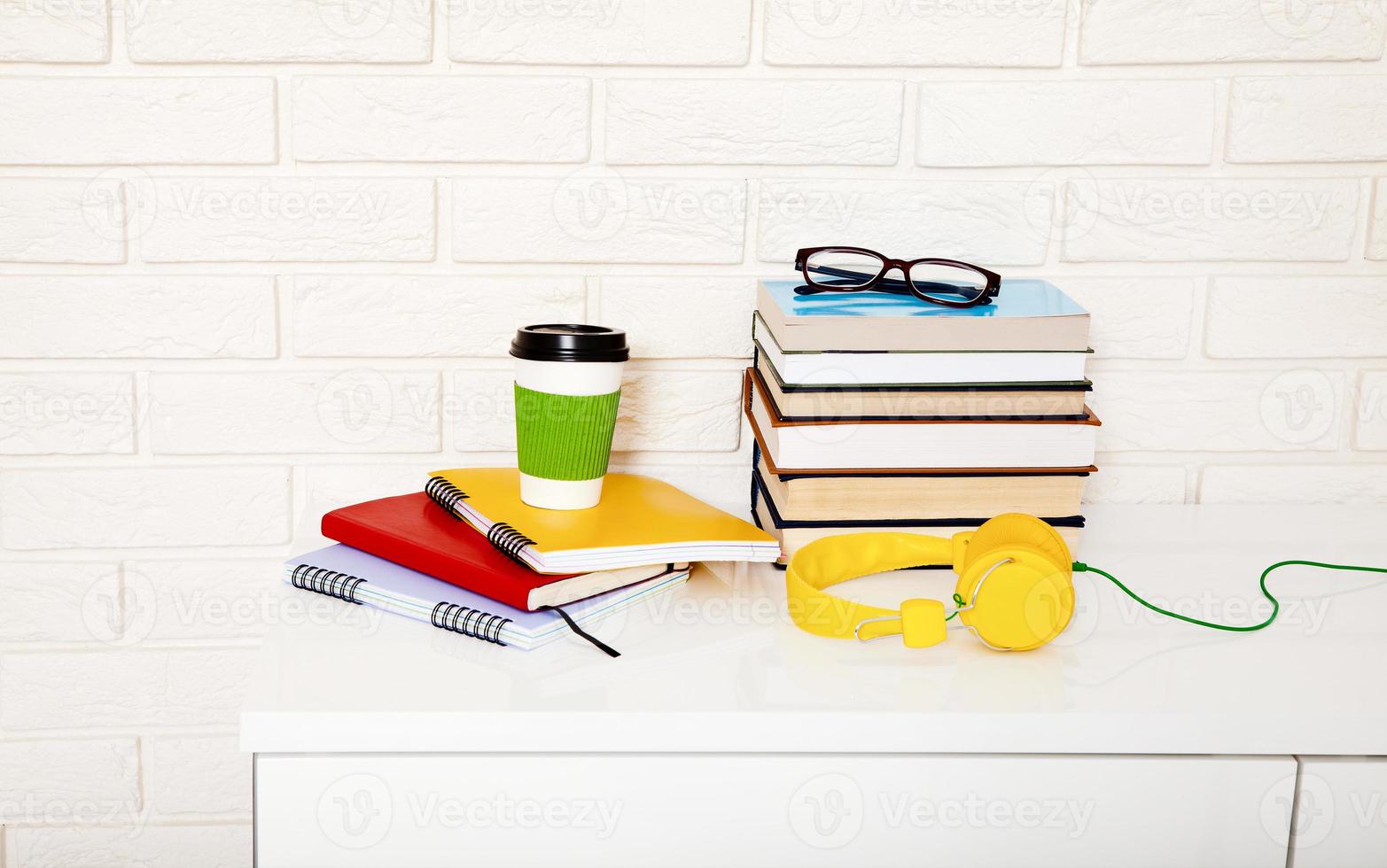 accessori per l'area di lavoro e l'istruzione sul tavolo. tazza di caffè, libri, occhiali, quaderni, cuffie. educazione allo stelo foto