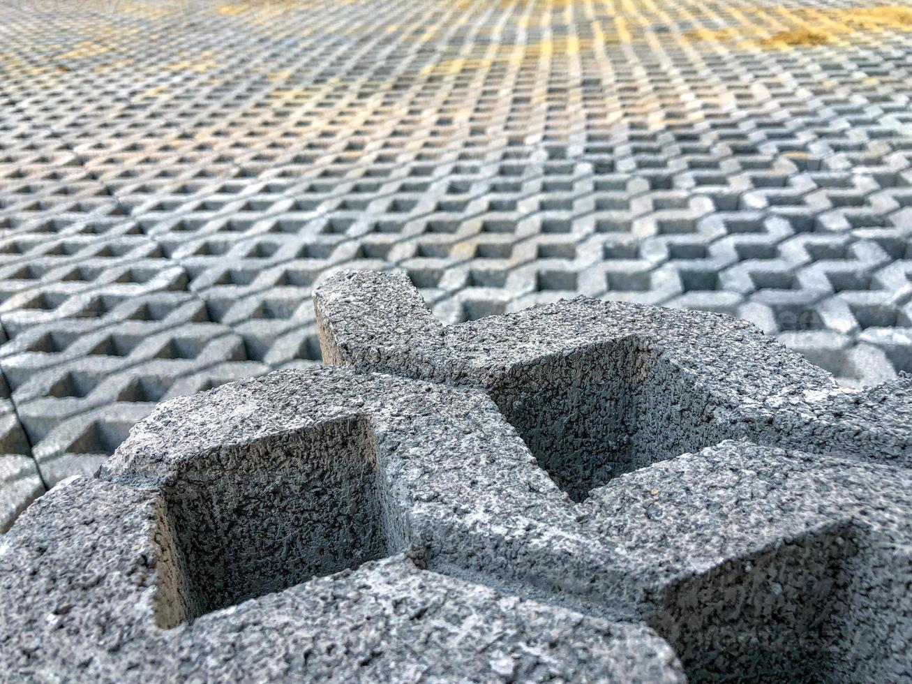 piastrella per pavimento a blocchi di mattoni in pietra di colore grigio con erba verde e sabbia come sfondo o texture. foto