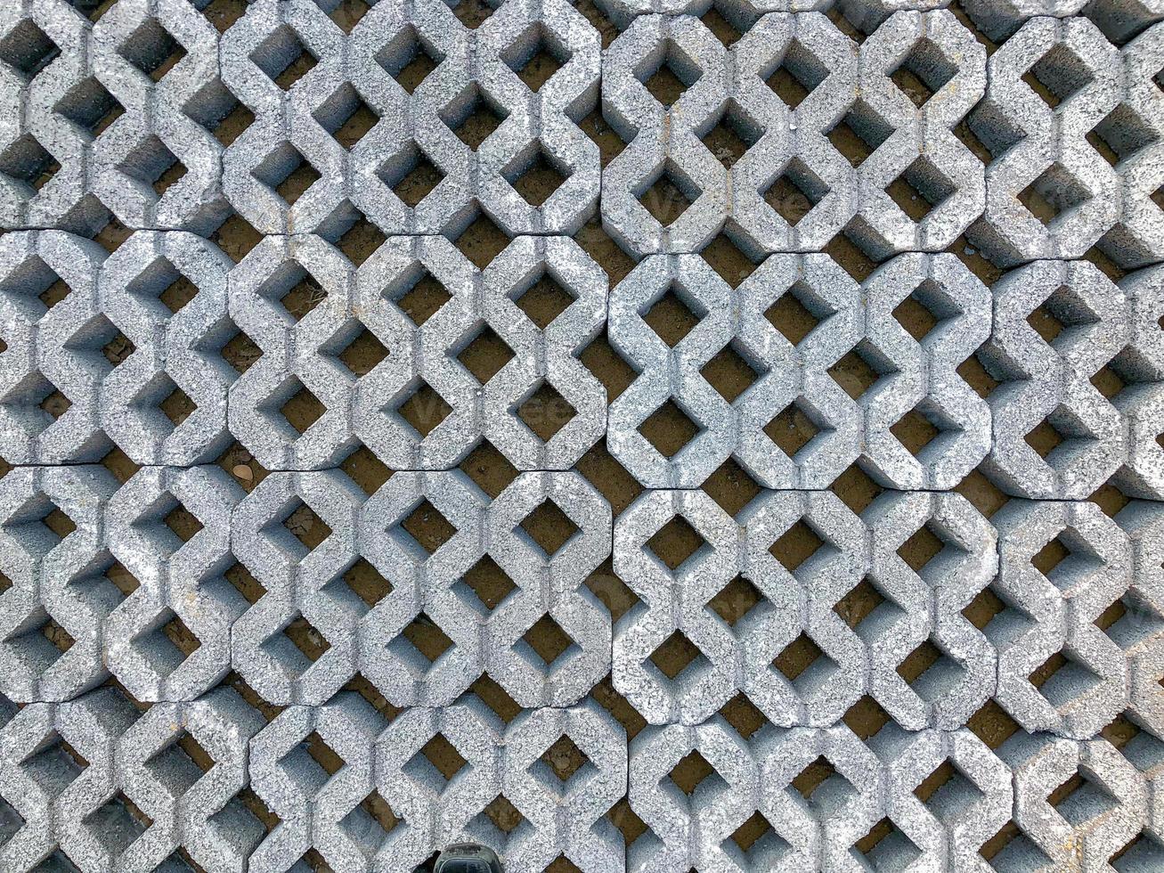 piastrella per pavimento a blocchi di mattoni in pietra di colore grigio con erba verde e sabbia come sfondo o texture. foto