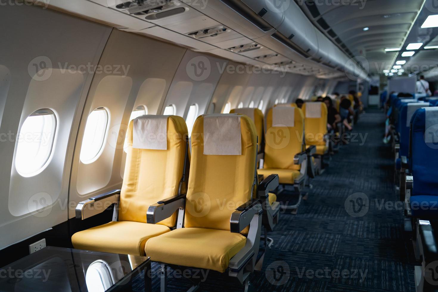 righe di passeggeri aereo posti a sedere nel il cabina.interni di commerciale aereo su loro posti a sedere durante volo economia classe passeggeri sezione di aereo. foto