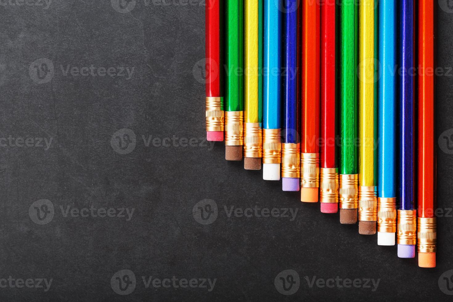 colorato matite con gomme da cancellare nel un' riga su un' nero sfondo foto