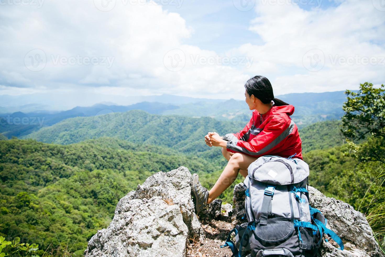 giovane persona escursioni a piedi femmina seduta su superiore roccia, zaino donna guardare a bellissimo montagna valle a luce del sole nel estate, paesaggio con sport ragazza, alto colline, foresta, cielo. viaggio e turismo. foto