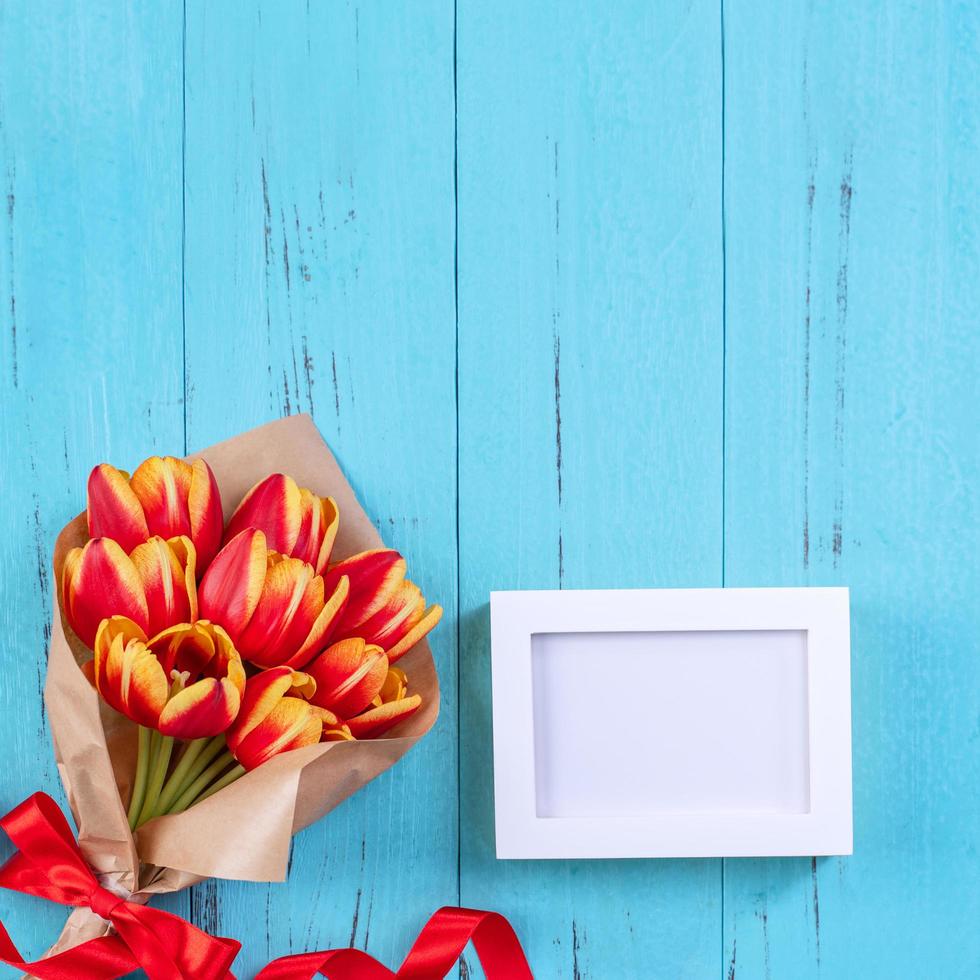 La madre di giorno sfondo, tulipano fiore mazzo - bellissimo rosso, giallo mazzo isolato su blu di legno tavolo, superiore Visualizza, piatto posizione, finto su design. foto