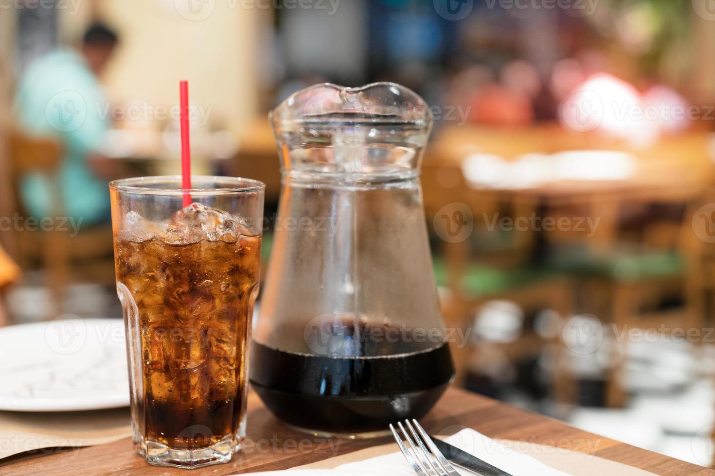 Coca Cola acqua e ghiaccio nel bicchiere con vaso nel ristorante foto