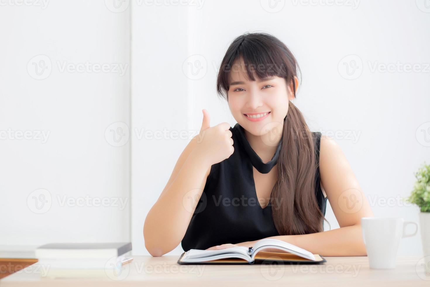 bellissimo ritratto giovane donna asiatica sorridente seduta studio e apprendimento scrittura taccuino e diario in soggiorno a casa, compiti ragazza, donna d'affari che lavora sul tavolo, concetto di educazione. foto