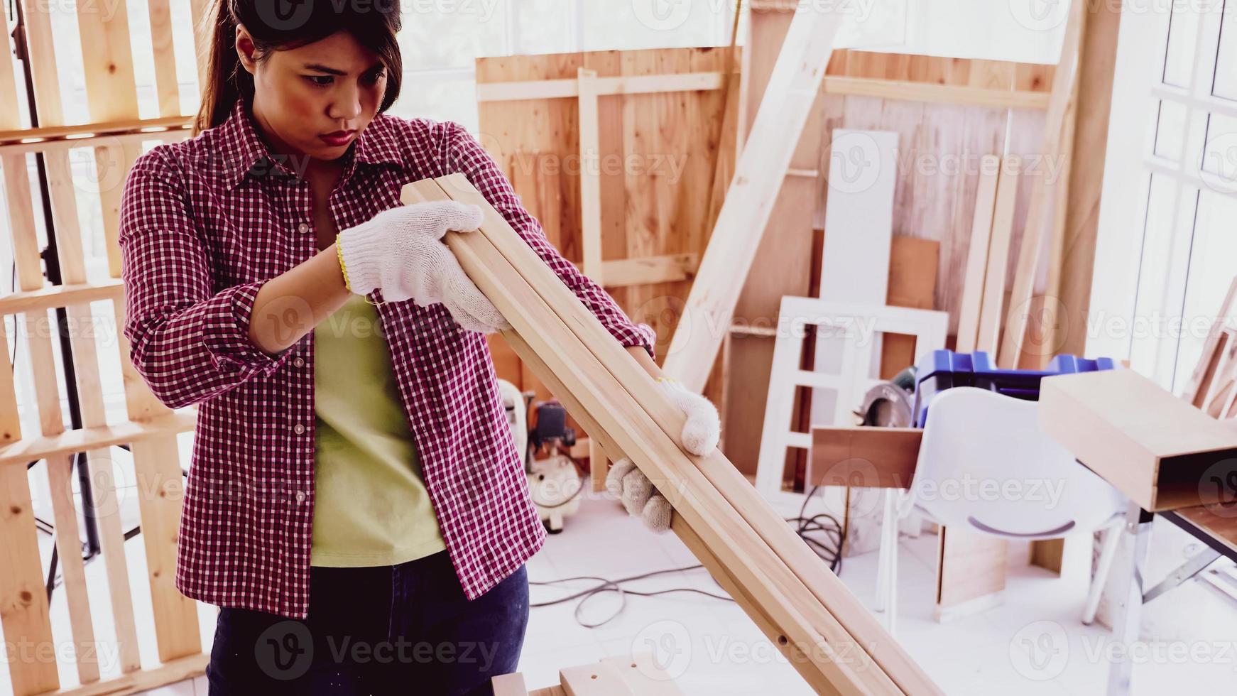 femmina falegname Tenere e confrontando dimensione di pezzi di tavole a luogo. foto