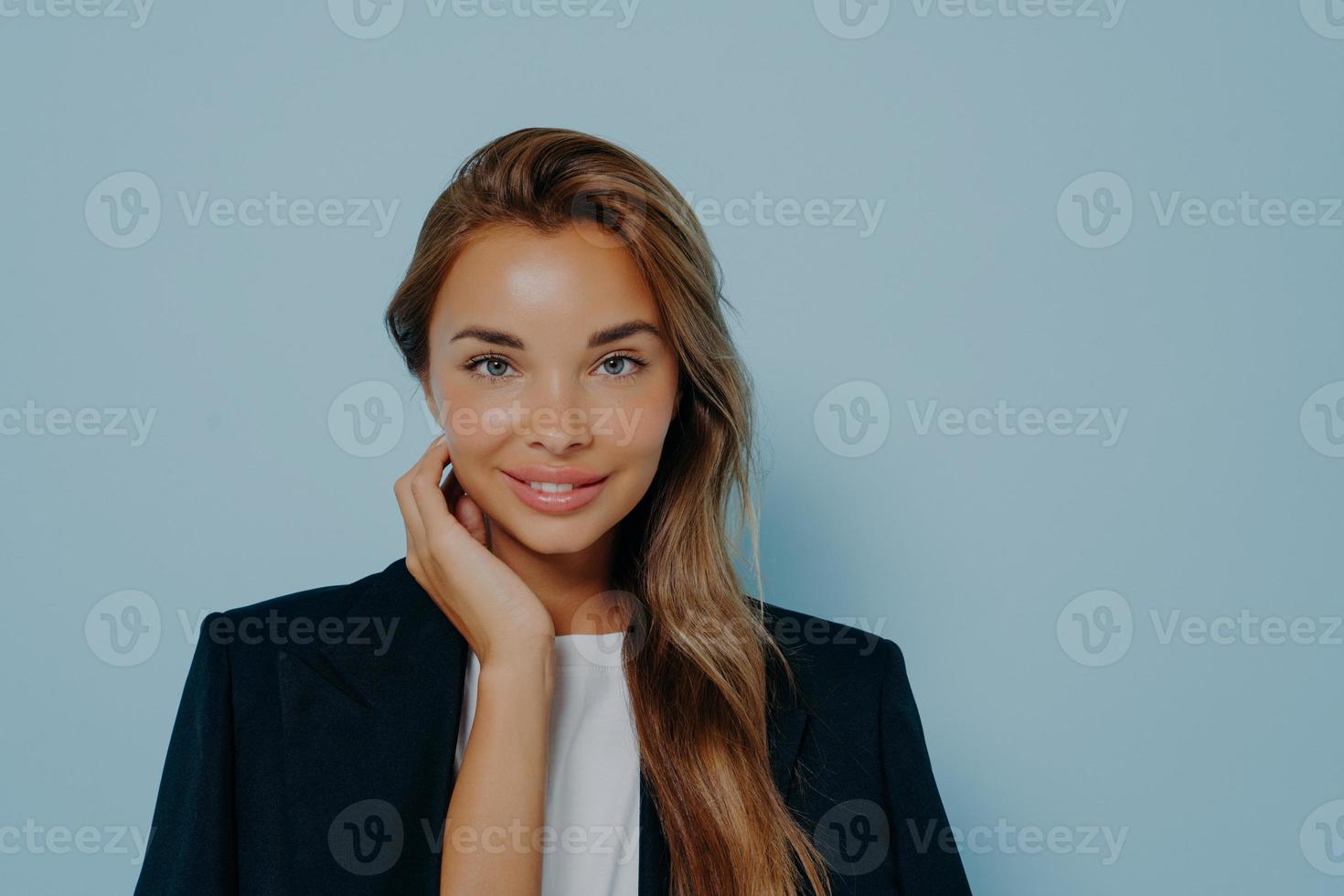 donna attraente con un sorriso gentile su sfondo azzurro foto