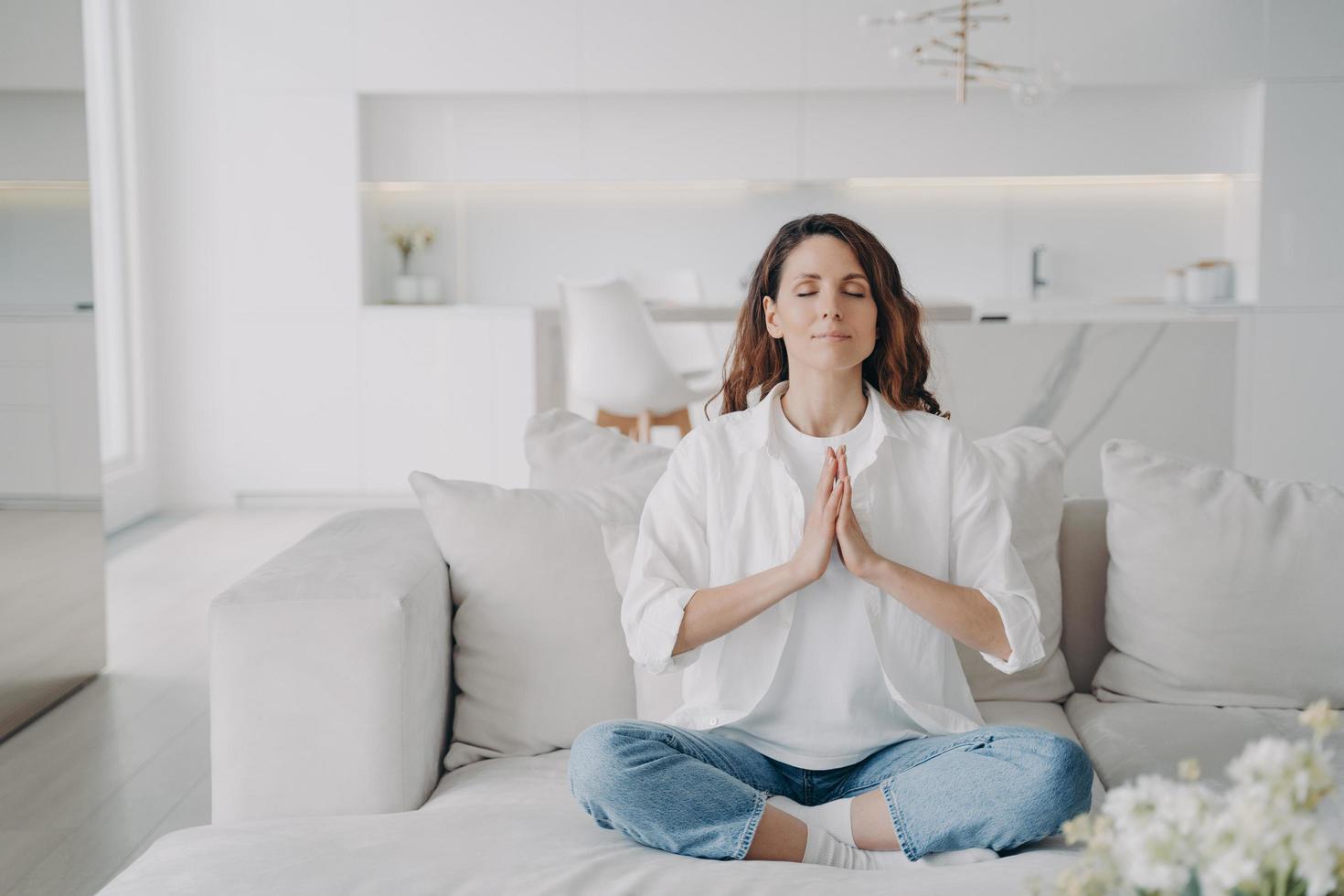 serena giovane donna latina che pratica yoga e esercizi di postura, loto asana a casa. foto