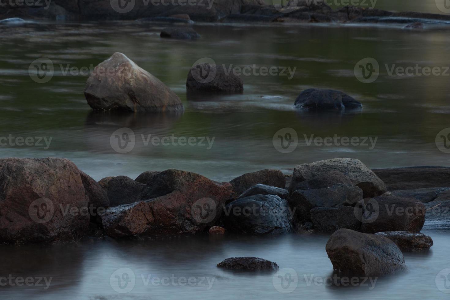 un' lungo esposizione Immagine di acqua fluente in giro roccia. foto