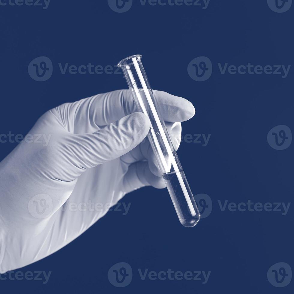 mano Tenere liquido nel test tubo vicino su isolato su un' blu sfondo. foto