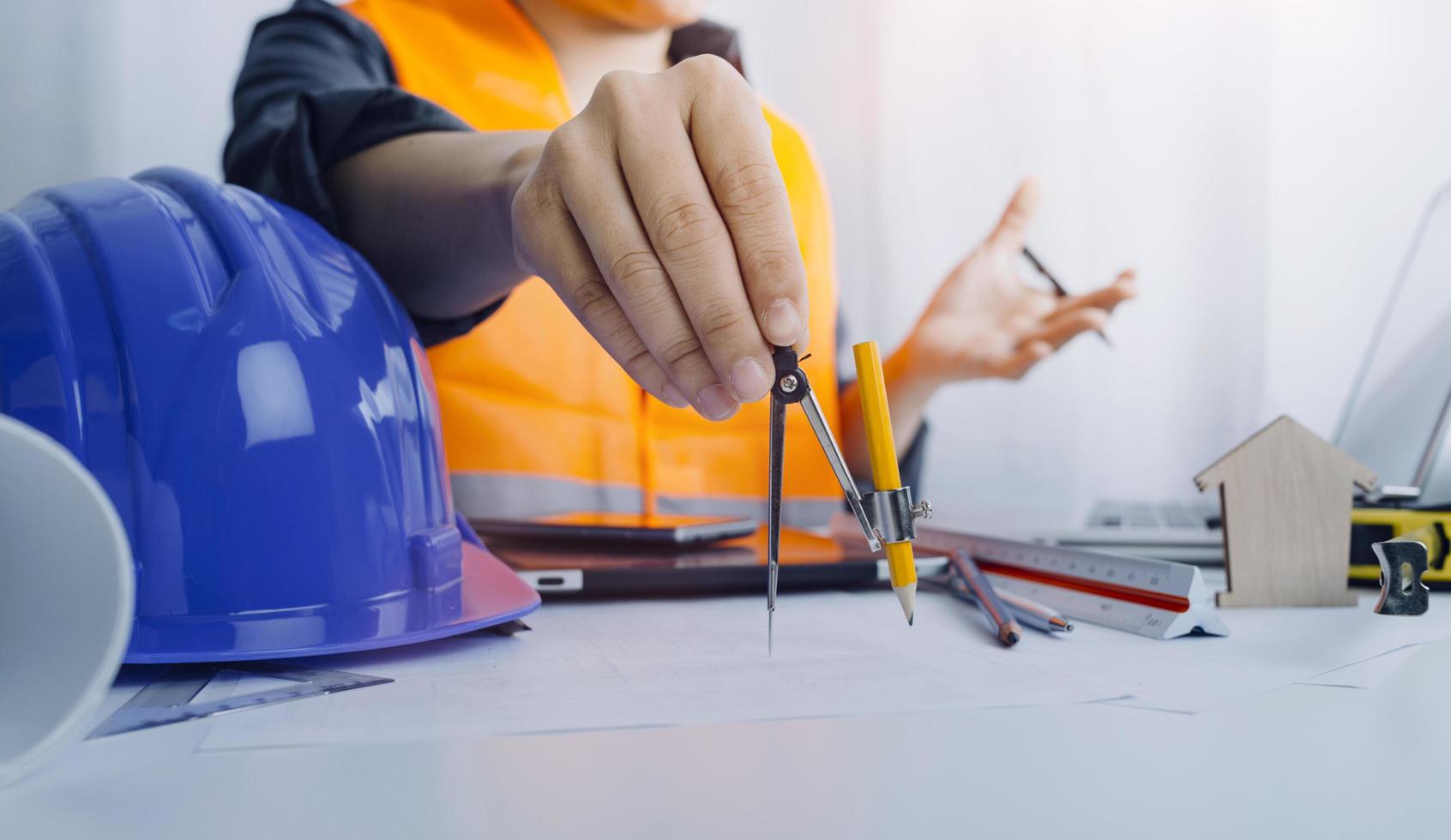 due colleghi che discutono di dati di lavoro e tablet, laptop con sul progetto architettonico in cantiere alla scrivania in ufficio foto