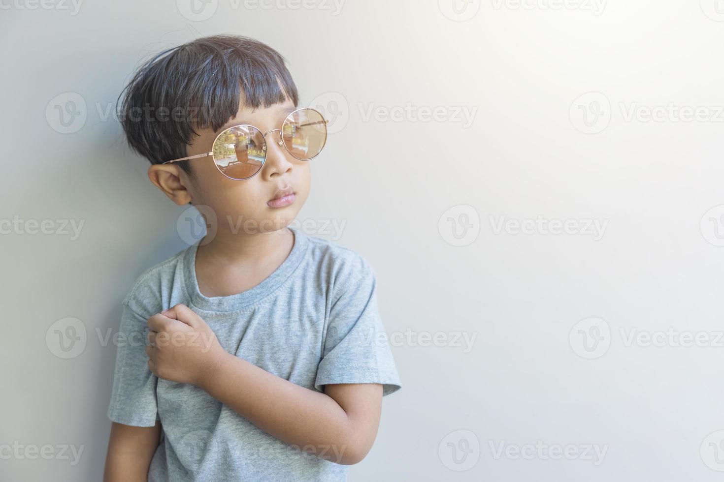 ritratto di un' contento giovane ragazzo di Asia origine nel un' grigio camicia e occhiali da sole Guarda a il telecamera foto