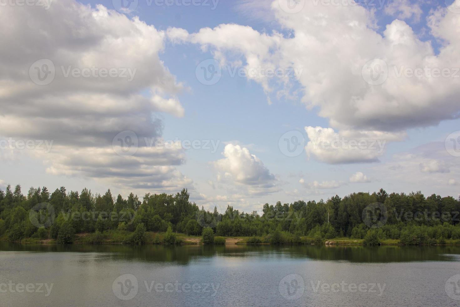 paesaggio estivo con un bellissimo lago con abeti e montagne boscose contro un cielo nuvoloso foto