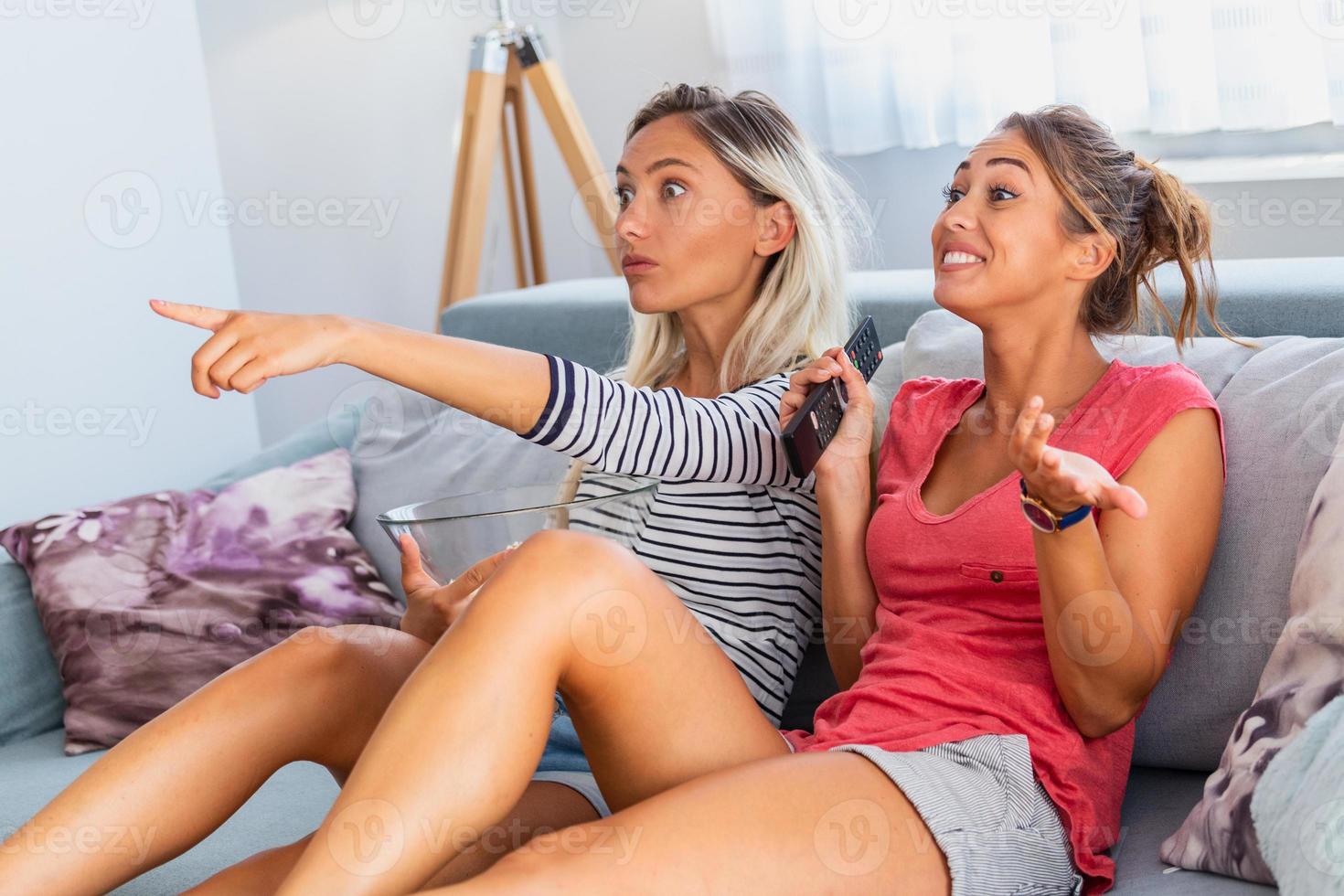 ritratto di divertente e contento giovane donne Guardando commedia nel letto e ridendo. allegro amici mangiare gustoso Popcorn e guardare film con letizia. accogliente e amichevole atmosfera foto