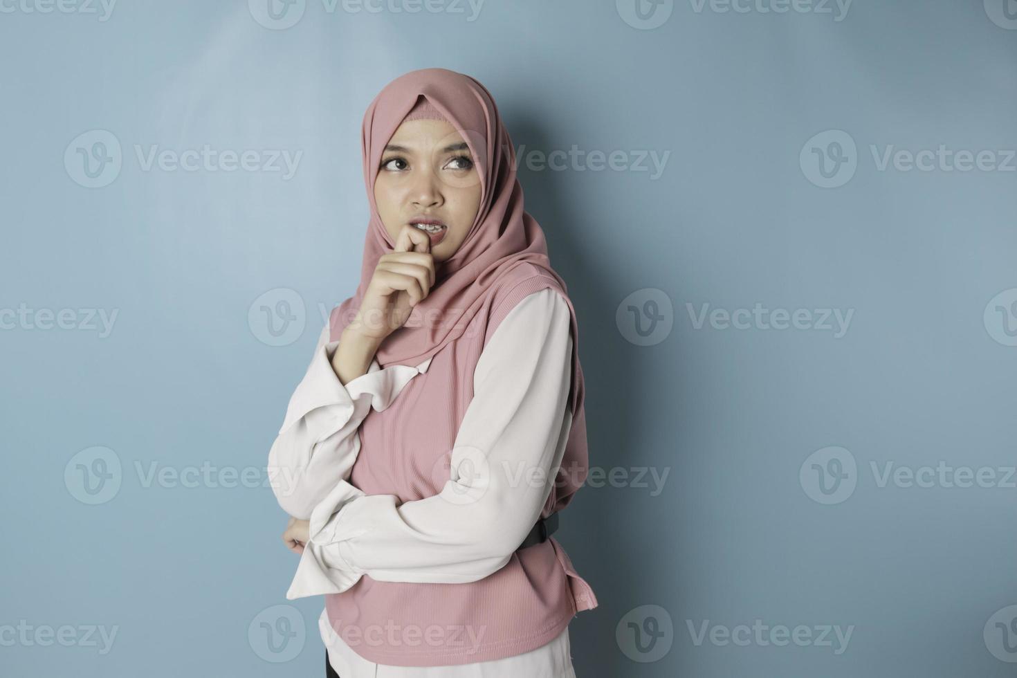 ritratto di un' riflessivo giovane musulmano donna indossare rosa hijab guardare a parte foto