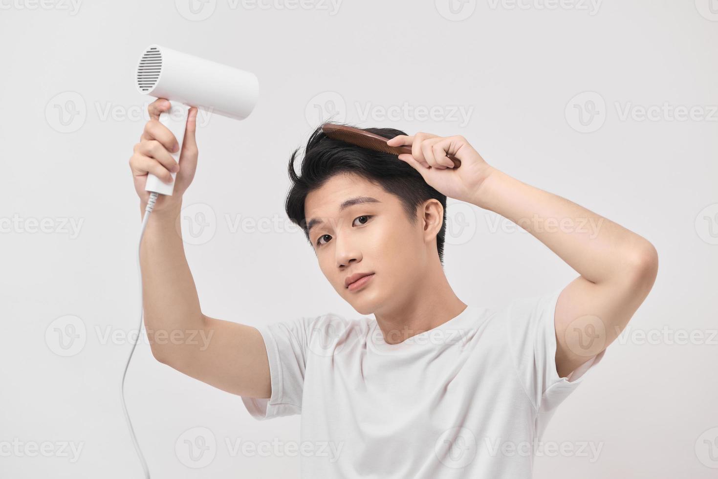 asiatico divertimento giovane uomo 20s anni vecchio nel bianca camicia hold soffio asciutto capelli isolato su bianca sfondo, foto