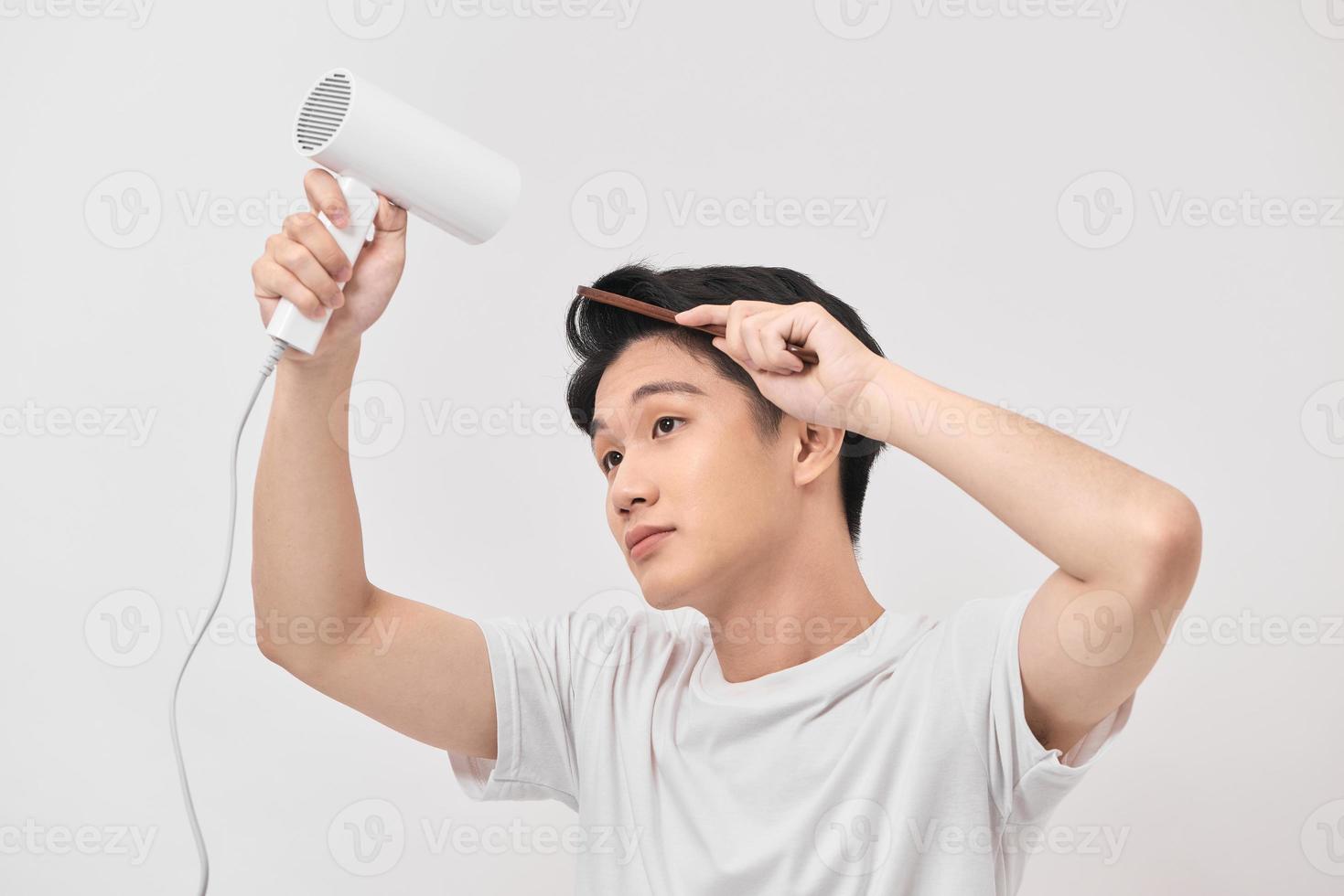 giovane asiatico uomo Tenere capelli asciugatrice e pettine la creazione di nuovo pettinatura su bianca sfondo foto