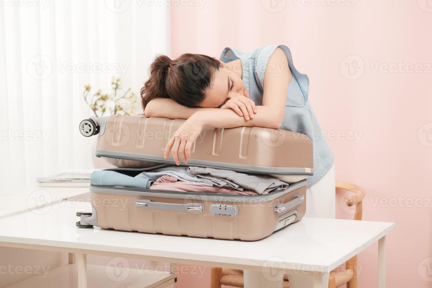 donna provando per in forma tutti capi di abbigliamento per Imballaggio sua valigia prima vacanza foto