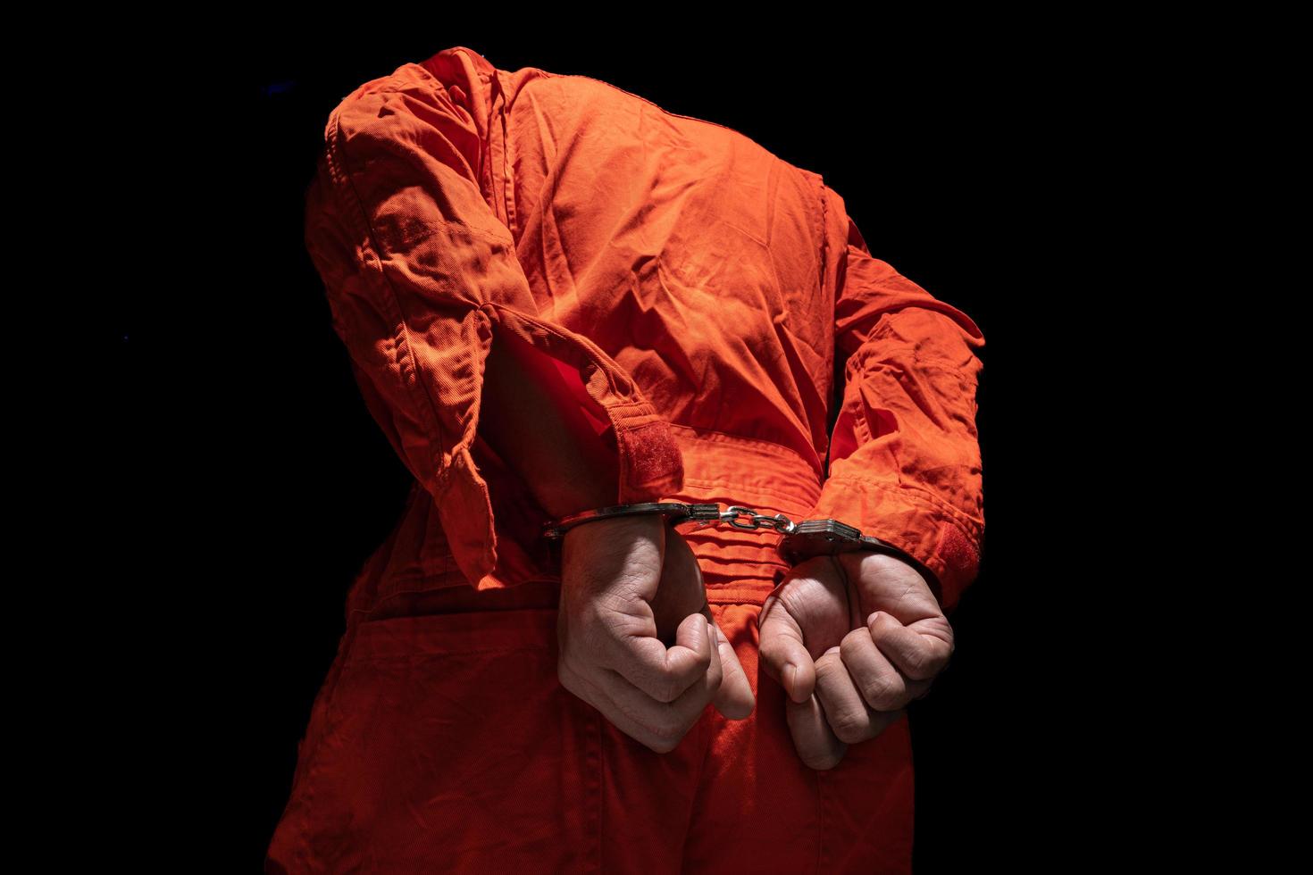 manette su accusato penale nel arancia prigione tuta. legge colpevole condannato per servire prigione volta, nel nero sfondo foto