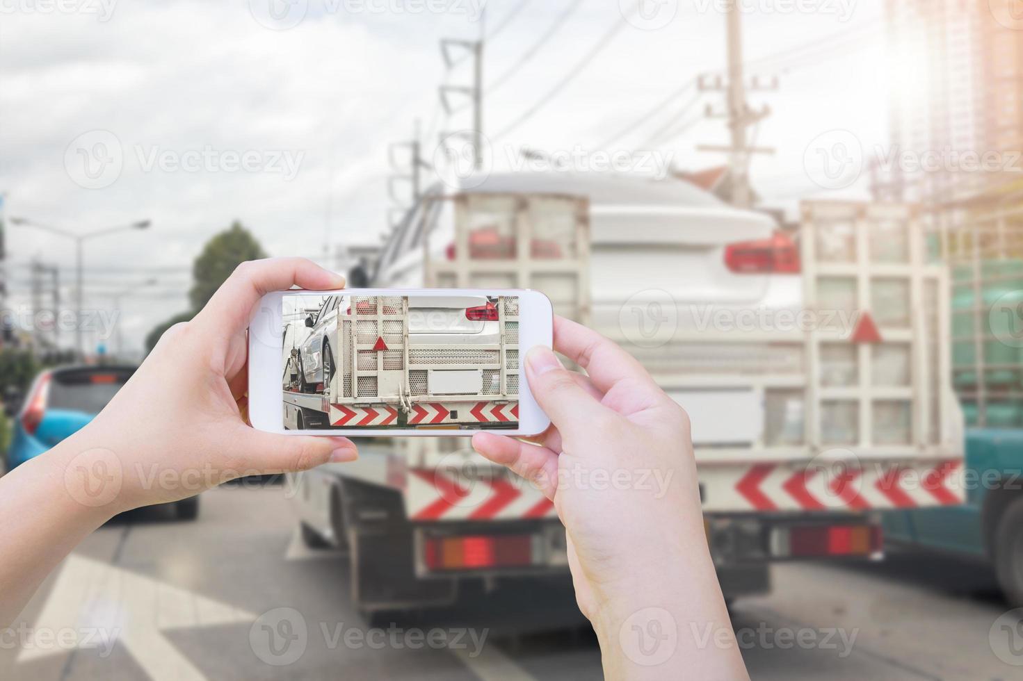 utilizzando smartphone fotografia il rotto auto su trainare camion dopo traffico incidente per auto assicurazione foto