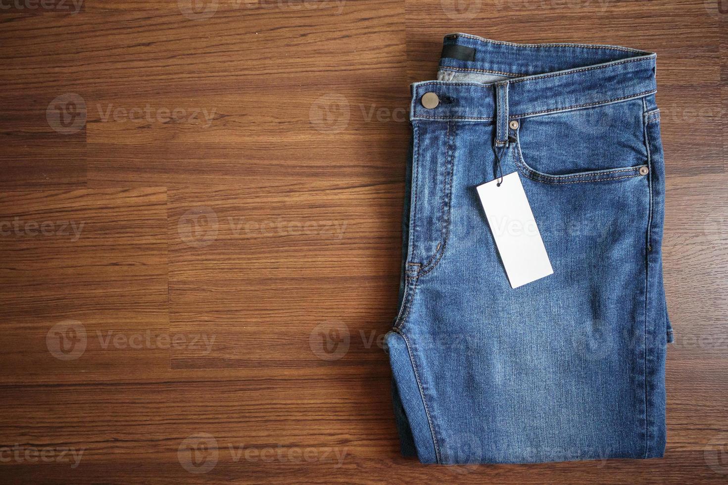 blue jeans con etichetta di prezzo bianca vuota su fondo di legno foto