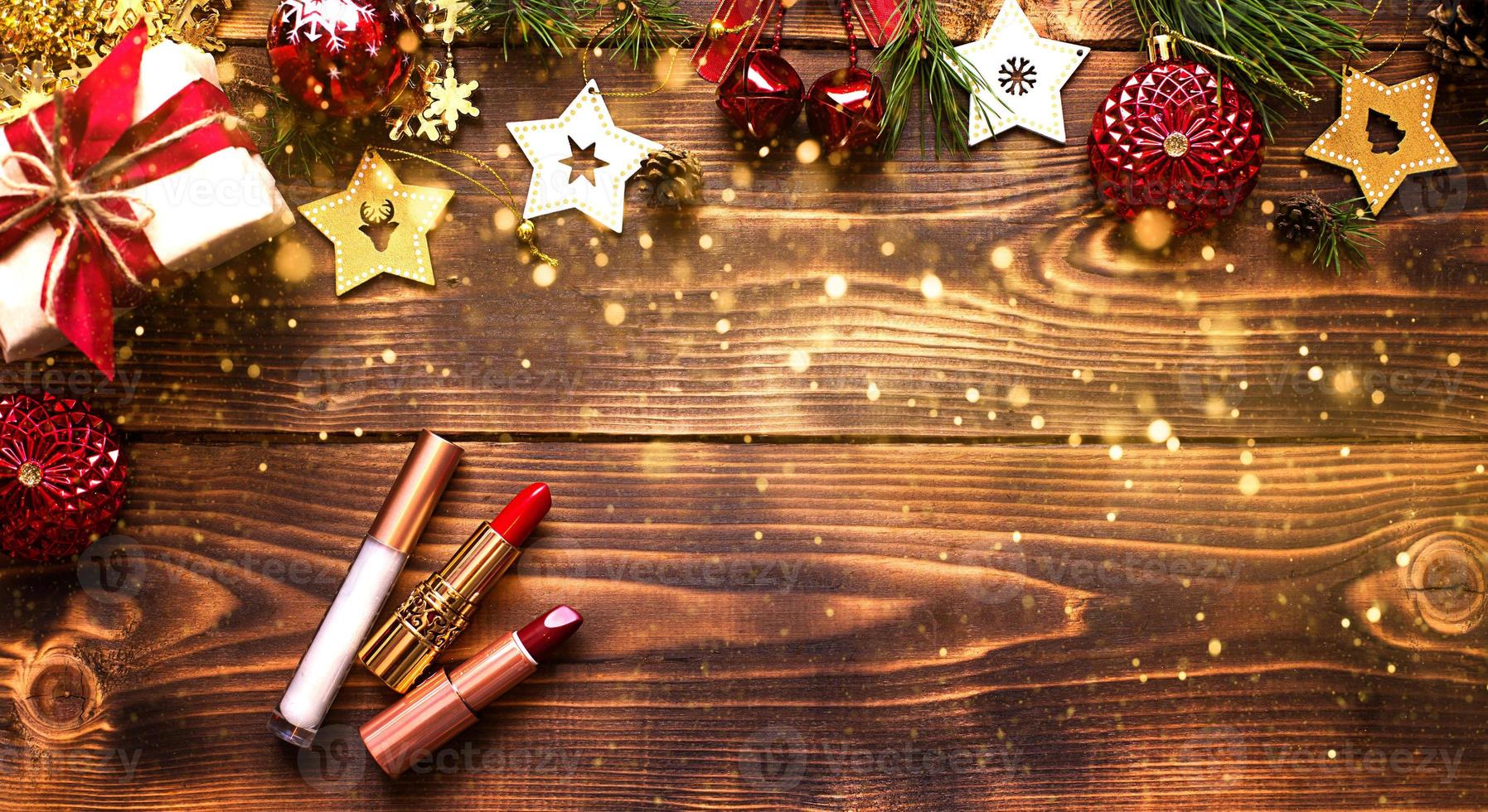 rossetto rosso e lucidalabbra e palpebre su uno sfondo di legno nell'arredamento natalizio. trucco per le vacanze per il nuovo anno, regalo, shopping, desideri delle donne. spazio per il testo, disposizione piatta foto