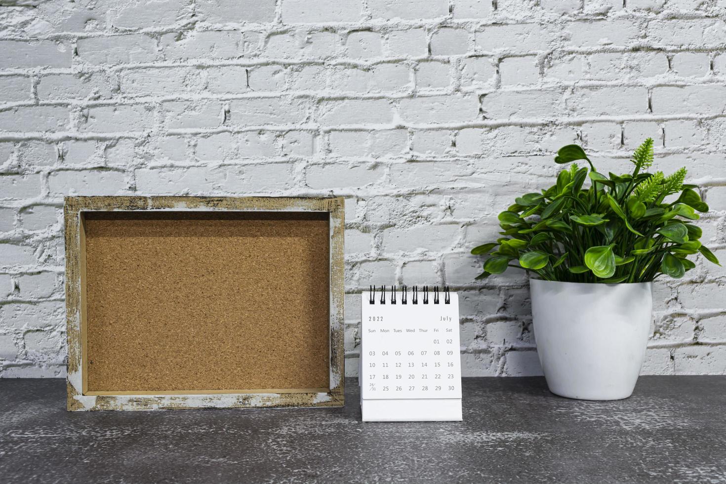 luglio 2022 bianca calendario con di legno telaio e in vaso pianta su di legno scrivania. foto